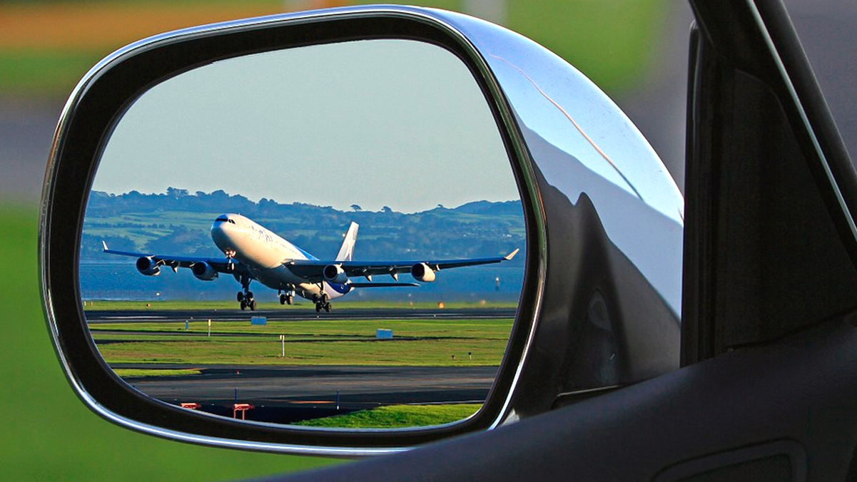 Un avión a punto de despegar visto desde el retrovisor de un coche / PIXABAY