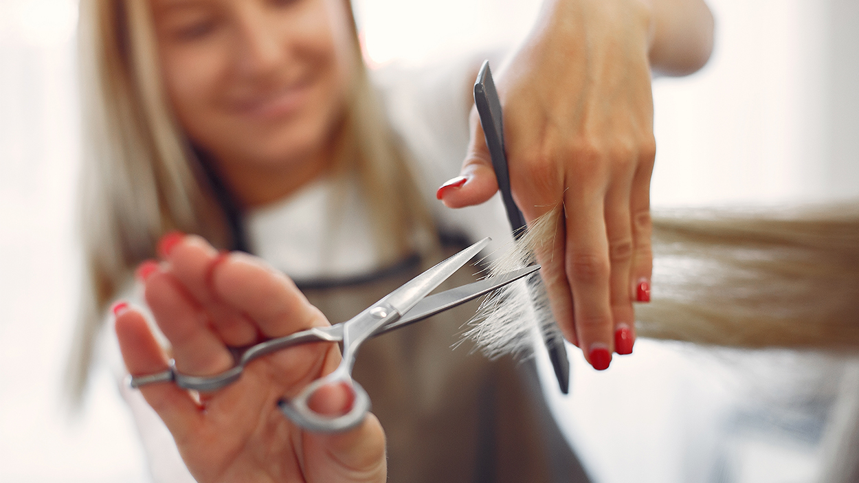 Una peluquera corta el pelo a una clienta en la peluquería / PROSTOOLEH