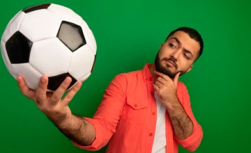 Un hombre piensa mientras sostiene un balón de fútbol / STOCKKING - FREEPIK